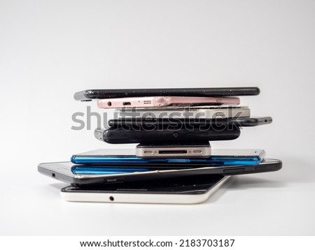 Old smartphones lie on top of each other. Stack of old mobile phones. Smartphones on a white background. Royalty-Free Stock Photo #2183703187