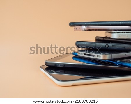 Old smartphones lie on top of each other. Stack of old mobile phones. Smartphones on an orange background. Royalty-Free Stock Photo #2183703215