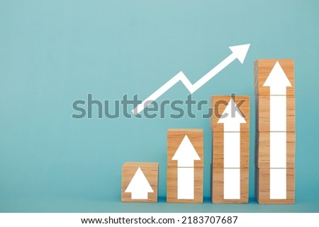Wooden block signs and symbols with up arrow financial and business growth interest rates and mortgage rates interest on investment inflation concept on blue background.