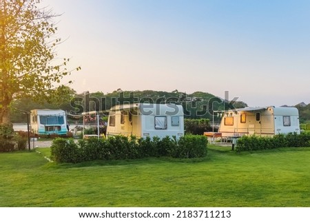 Cozy retro travel trailer Caravan on green grass before sunset near riverside in peaceful countryside. Family vacation travel RV, holiday trip in motorhome. Outdoor and Recreational Vehicles Theme. Royalty-Free Stock Photo #2183711213