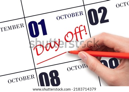 1st day of October. Hand writing text DAY OFF and drawing a line on calendar date 1 October. Vacation planning concept. Autumn month, day of the year concept.