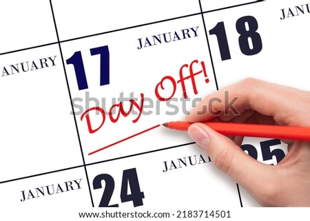 17th day of January. Hand writing text DAY OFF and drawing a line on calendar date 17 January. Vacation planning concept. Winter month, day of the year concept.