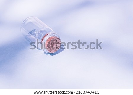 Modern apothecary concept. Empty glass miniature bottle with cork cap on a violet background. Still life compositions