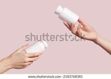 Hands holding blank white plastic tubes on pink background. Packaging for pills, capsules or supplements. Medic product branding mockup. High quality photo Royalty-Free Stock Photo #2183768381