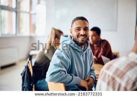 Happy college student having a lecture in the classroom and looking at camera.