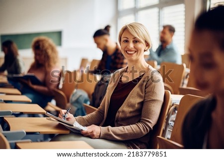 Happy mid adult woman attending a class at the university and looking at camera. Royalty-Free Stock Photo #2183779851