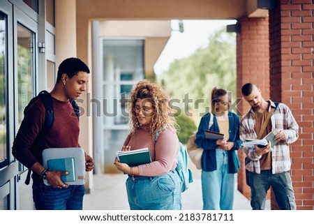 African American student and his female friend communicating in front of university building. Royalty-Free Stock Photo #2183781711