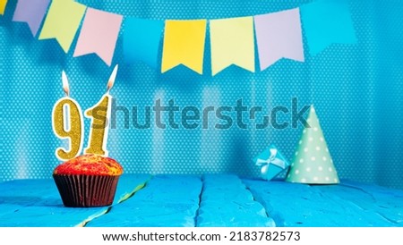 Happy birthday card with a muffin decorated with a festive cake and burning candles. Copy space. Beautiful background happy birthday on the background of blue boards with a number of candles number 91