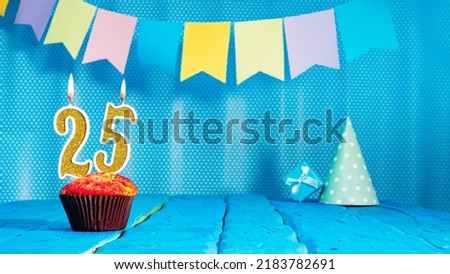 Happy birthday card with a muffin decorated with a festive cake and burning candles. Copy space. Beautiful background happy birthday on the background of blue boards with a number of candles number 25