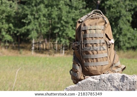 Brown military backpack close-up on the background of nature. Soldier's personal belongings.