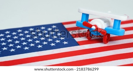 The toy plane stands on the US flag. Travel and business concept