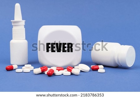 Medical concept. On the blue surface of the pill, capsule, spray, jar and cube with the inscription - FEVER