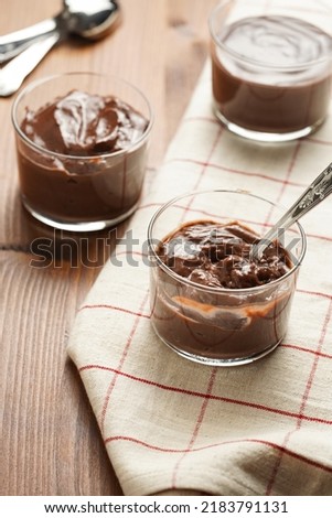 Creamy french chocolate ganache or pudding in glass on linen napkin on wooden background, three glasses