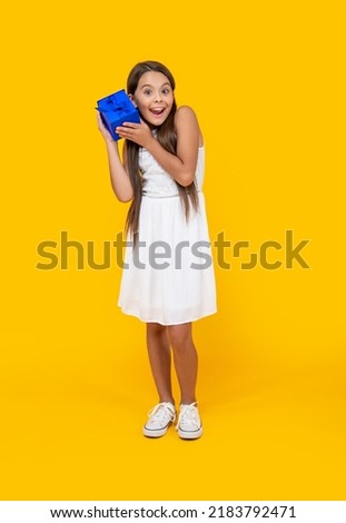 amazed teen girl hold present box on yellow background