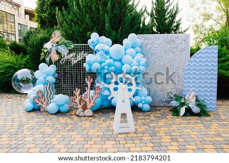 photo zone and decorations for the holiday in marine style in the fresh air. blue balloons and steering wheel. organization of the party.