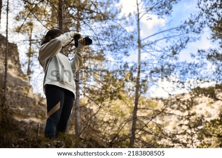 young girl taking pictures in the forest