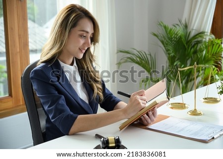 A beautiful and professional young Asian female lawyer notes something on her personal book planner in the office.
