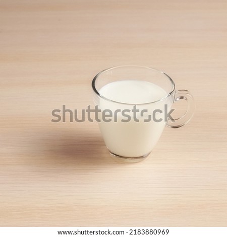 Transparent cup with milk on a wooden table. Delicious Drink