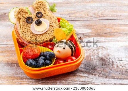 Kids lunch box with funny bear sandwich and boiled egg bee, apple, orange juice. Back to school background. Copy space Royalty-Free Stock Photo #2183886865
