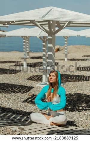 Young beautiful woman practicing yoga on the beach
