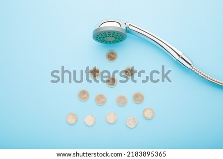 Euro coins as drops falling from shower head on light blue table background. Pastel color. Closeup. Water consumption and saving concept. Royalty-Free Stock Photo #2183895365
