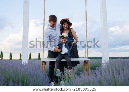 Happy family with son on swing in lavender field