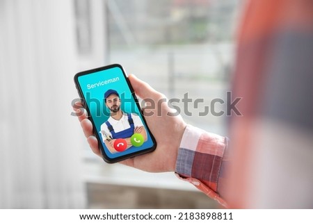 Man with smartphone calling professional serviceman indoors, closeup Royalty-Free Stock Photo #2183898811