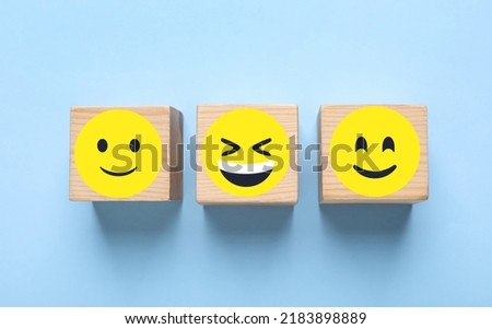 Wooden cubes with different emoticons on light blue background, flat lay