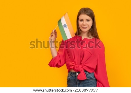 Beautiful young woman of European appearance with the flag of India on yellow background. Travel to India