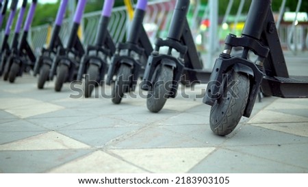Parking is a huge number of electric scooters near the green park in sunny weather. Charger for electric scooters 4k Royalty-Free Stock Photo #2183903105