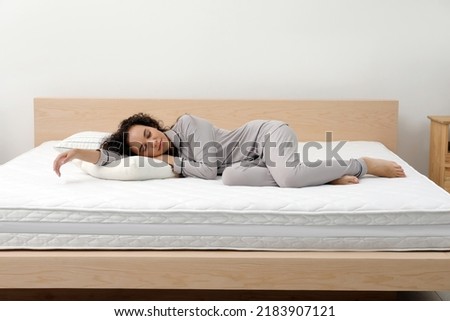Young African American woman sleeping on bed with comfortable mattress and pillow at home Royalty-Free Stock Photo #2183907121
