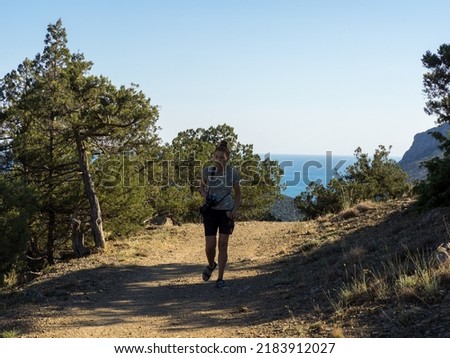 Woman with photo camera on the Golitsyn Trail in Novy Svet, Sudak, Crimea. Natural reserve juniper grove on the Crimean peninsula. Concept of tourism and travel