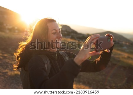 beautiful young girl travels and takes a photo on the phone. travel in the mountains. portrait of a girl with a phone at sunset.