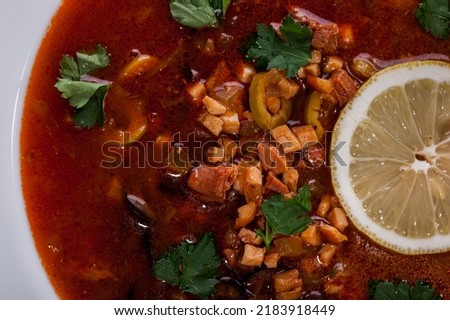 Soup with parsley, lemon, olives and meat in a plate on the table