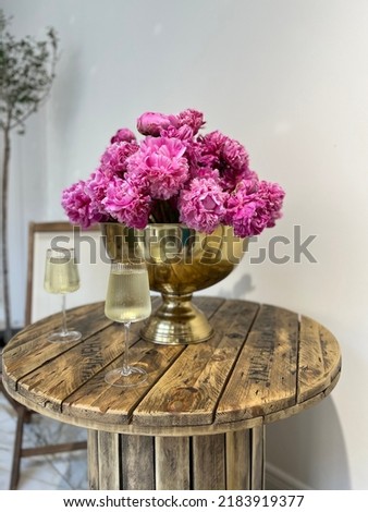 peonies in a vase.  pink flowers in a white room .romantic dinner with a glass of white wine