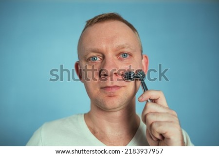 Man using facial roller for face massage. Beauty skin care