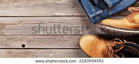 Men's clothes and accessories. Jeans and shoes on wooden background. Top view flat lay with copy space