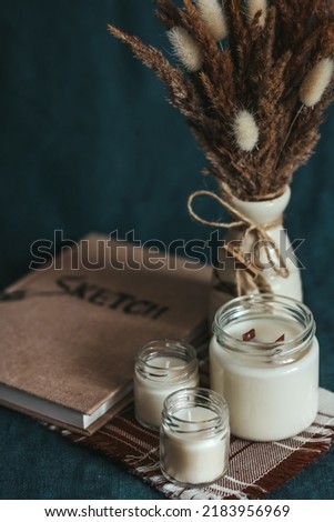 Scented candles in the interior. Interior details in milk colors. Combination of blue and beige. Candles in a glass