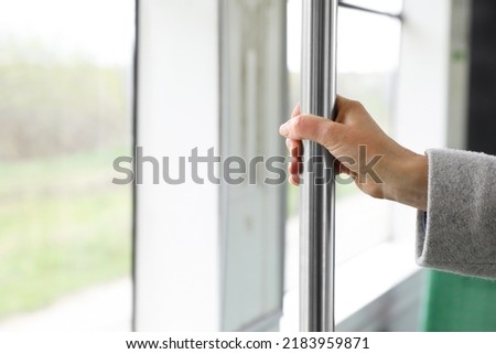 Woman holding grab pole near window in public transport, closeup. Space for text Royalty-Free Stock Photo #2183959871