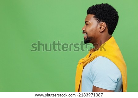 Side profile view young smiling happy cheerful fun cool satisfied man of African American ethnicity 20s wear blue t-shirt isolated on plain green background studio portrait. People lifestyle concept