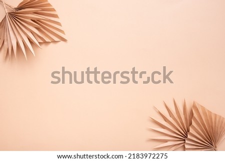 Decorative paper tropical palm dry leaves on beige background. Copy space.
