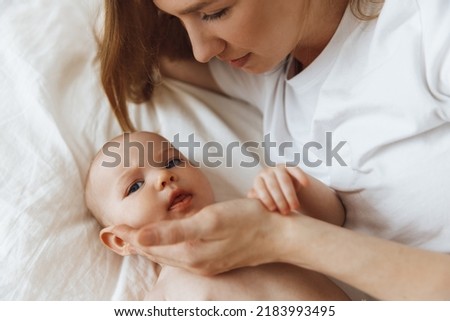 Portrait of a caring and loving mother kissing her little newborn daughter on the bed. beautiful mother playing with her little baby in the bedroom, top view. happy mother and child. Mother 