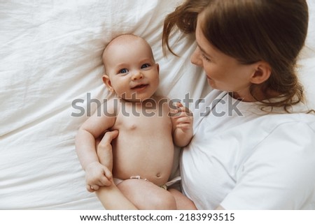 Portrait of a caring and loving mother kissing her little newborn daughter on the bed. beautiful mother playing with her little baby in the bedroom, top view. happy mother and child. Mother