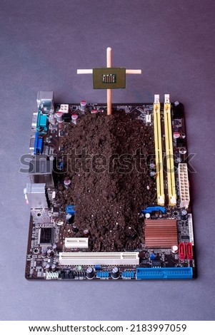 the computer board is covered with earth. the concept of scarcity of pc chips funeral grave on the motherboard. monument to the microprocessor video card on a gray background
