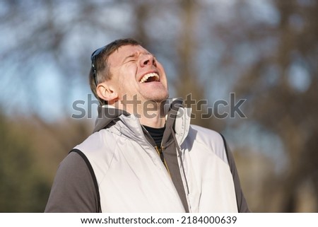 Photography of happy laughing handsome man. Portrait at sunny spring day on the city street. His mood is good, even excellent. Close up image like a promo action Royalty-Free Stock Photo #2184000639