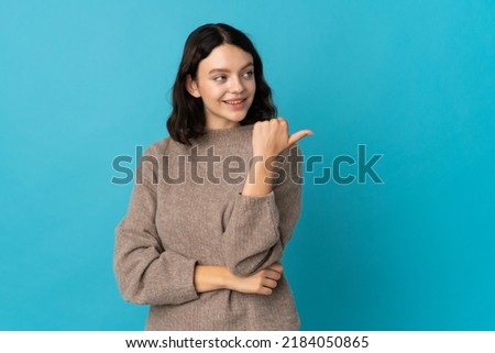 Teenager Ukrainian girl isolated on blue background pointing to the side to present a product