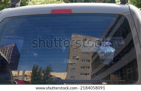 Distorted and defocused reflection of urban landscape in rear window of car. Abstract view for creative design.