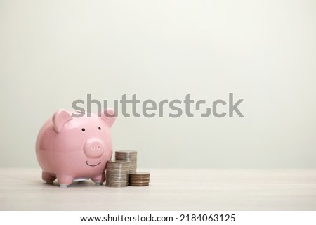 pink piggy bank smiling and coins on the table, for saving money wealth, and financial concepts, copy space Royalty-Free Stock Photo #2184063125