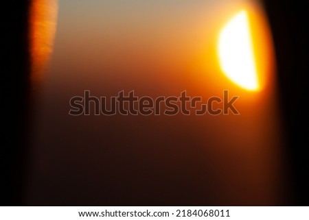 Abstract shot of the Sun setting through an airplane window during a flight