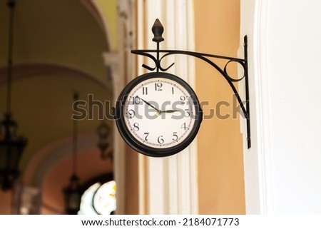Old fashioned analog clock hanging on building wall outdoors